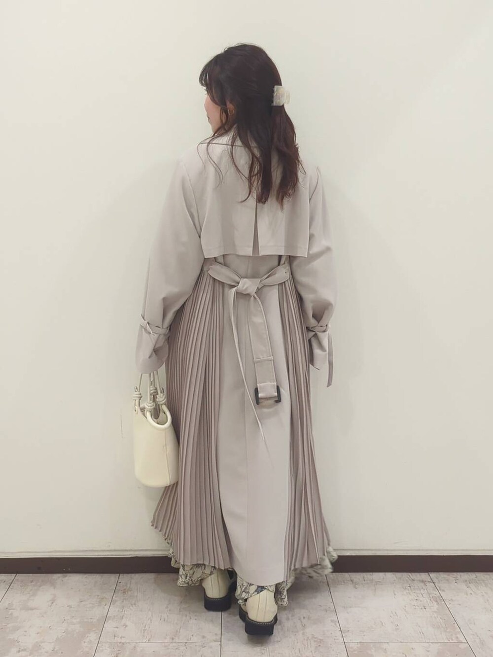 グレー系のニット/セーター、ホワイト系のハンドバッグ、ホワイト系のブーツを着用したレディースの春コーディネートの4枚目の写真