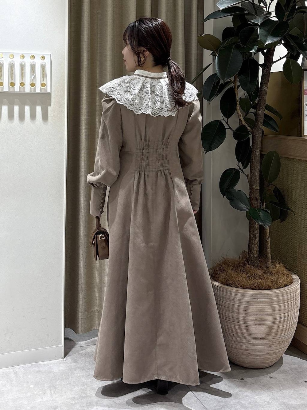 ブラウン系のブーツ、ブラウン系のショルダーバッグ、ベージュ系のワンピースを着用したレディースの冬コーディネートの3枚目の写真