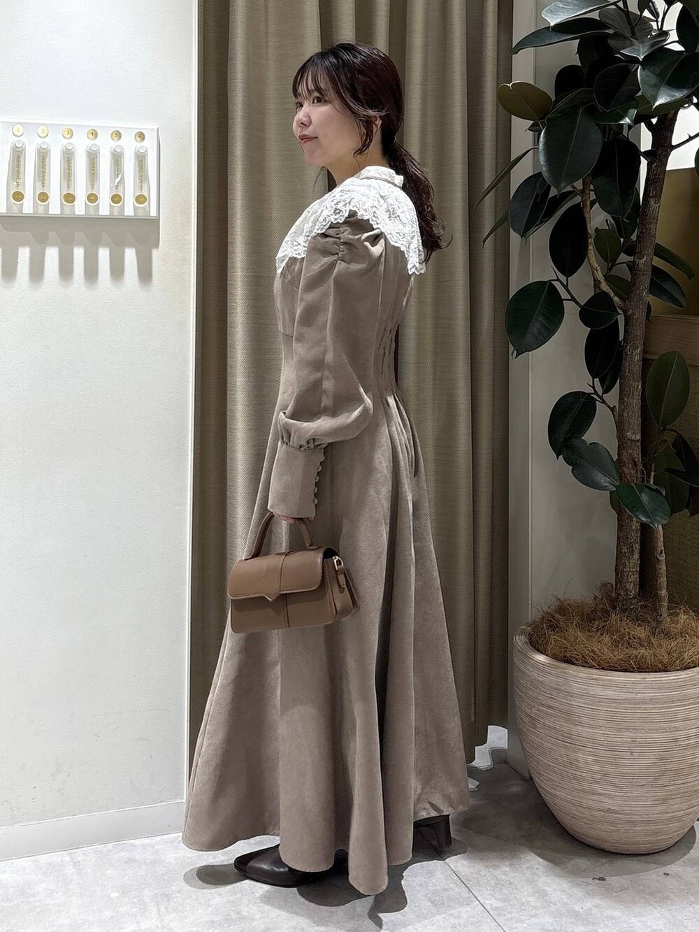 ブラウン系のブーツ、ブラウン系のショルダーバッグ、ベージュ系のワンピースを着用したレディースの冬コーディネートの2枚目の写真