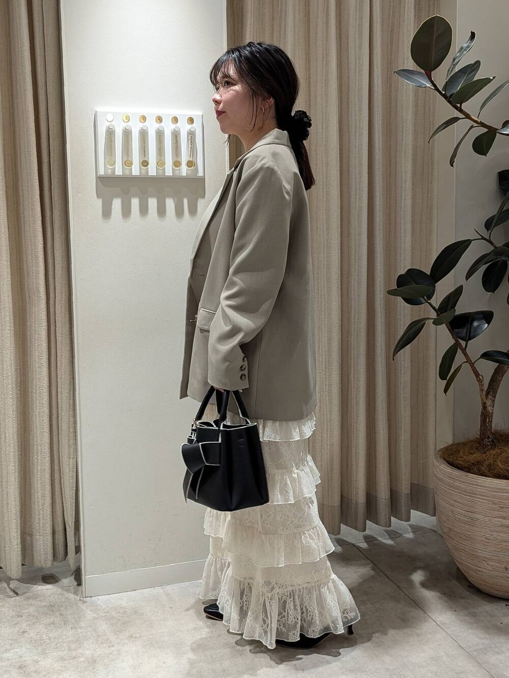 ブラック系のショルダーバッグ、ベージュ系のテーラードジャケット、ホワイト系のTシャツ/カットソーを着用したレディースの冬コーディネートの2枚目の写真