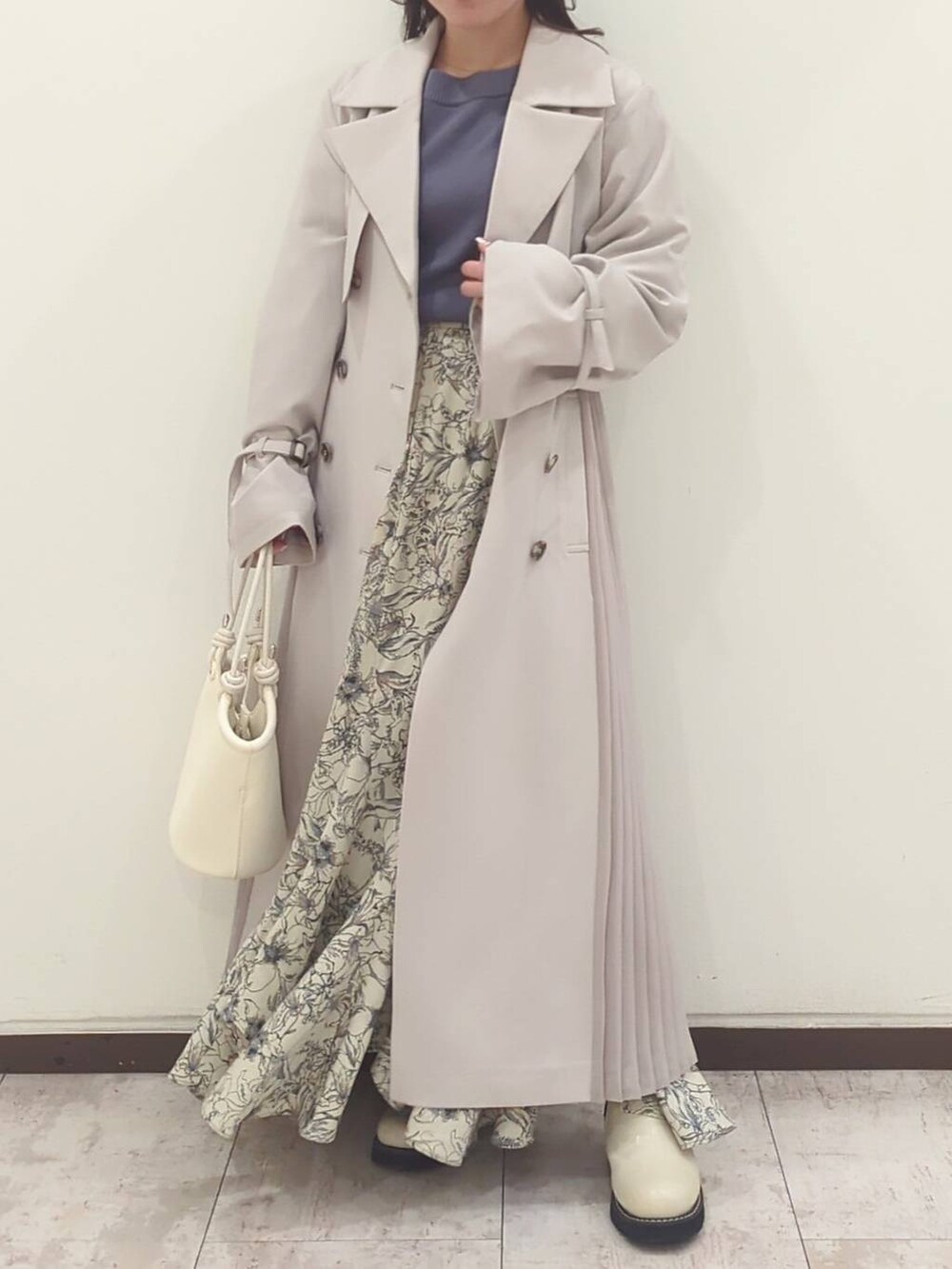 グレー系のニット/セーター、ホワイト系のハンドバッグ、ホワイト系のブーツを着用したレディースの春コーディネートの2枚目の写真