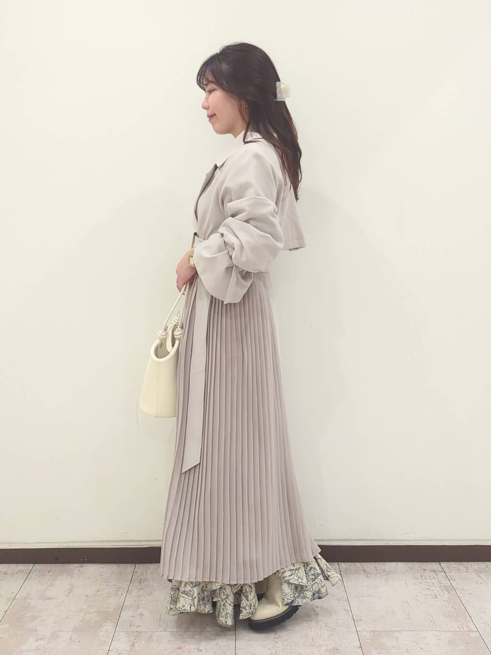 グレー系のニット/セーター、ホワイト系のハンドバッグ、ホワイト系のブーツを着用したレディースの春コーディネートの6枚目の写真