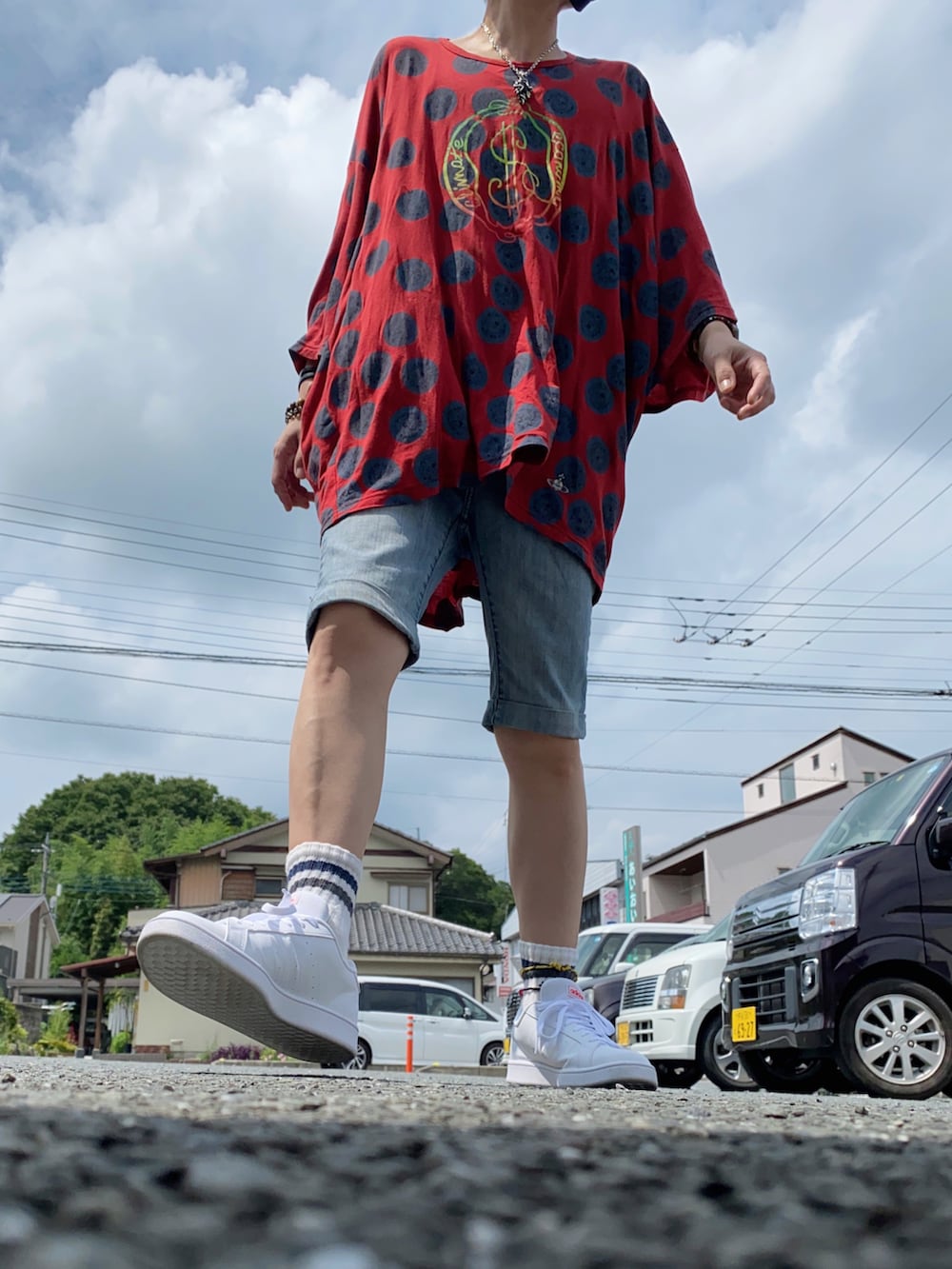 レッド系のTシャツ/カットソー、ホワイト系のスニーカー、ブルー系のデニムパンツを着用したメンズの夏コーディネートの2枚目の写真