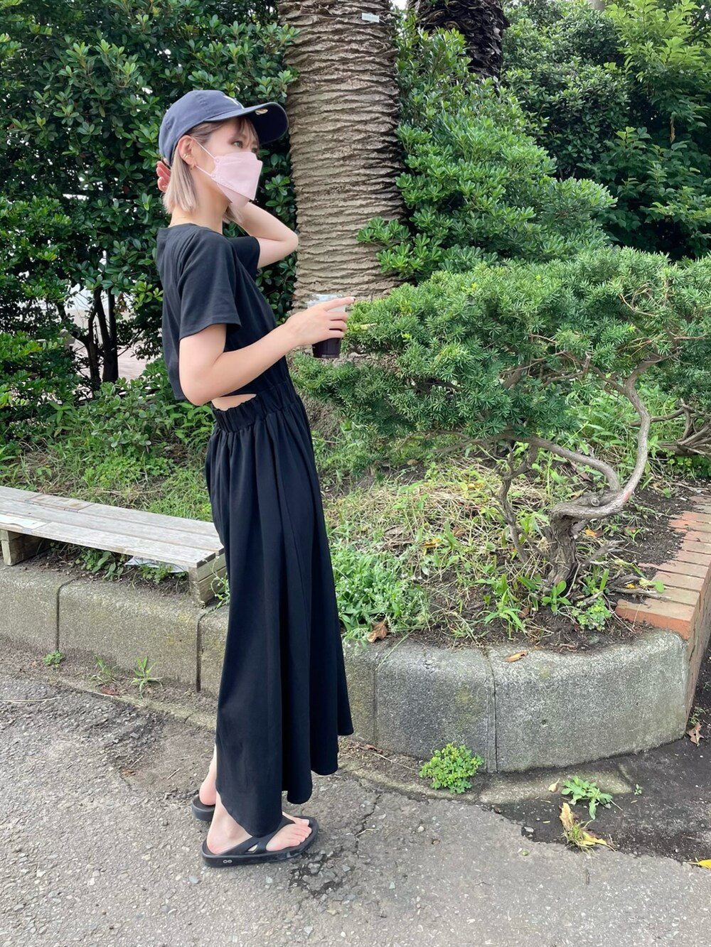ブラック系のワンピース、ブラック系のサンダル、ブルー系のキャップを着用したレディースの夏コーディネートの3枚目の写真