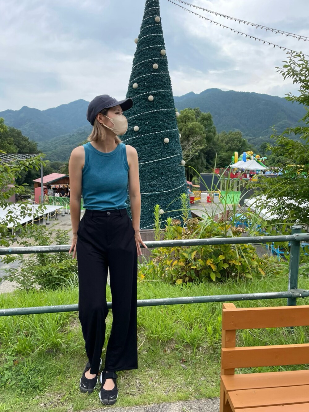 ブルー系のタンクトップ、ブラック系のスニーカー、ブルー系のキャップを着用したレディースの夏コーディネートの2枚目の写真