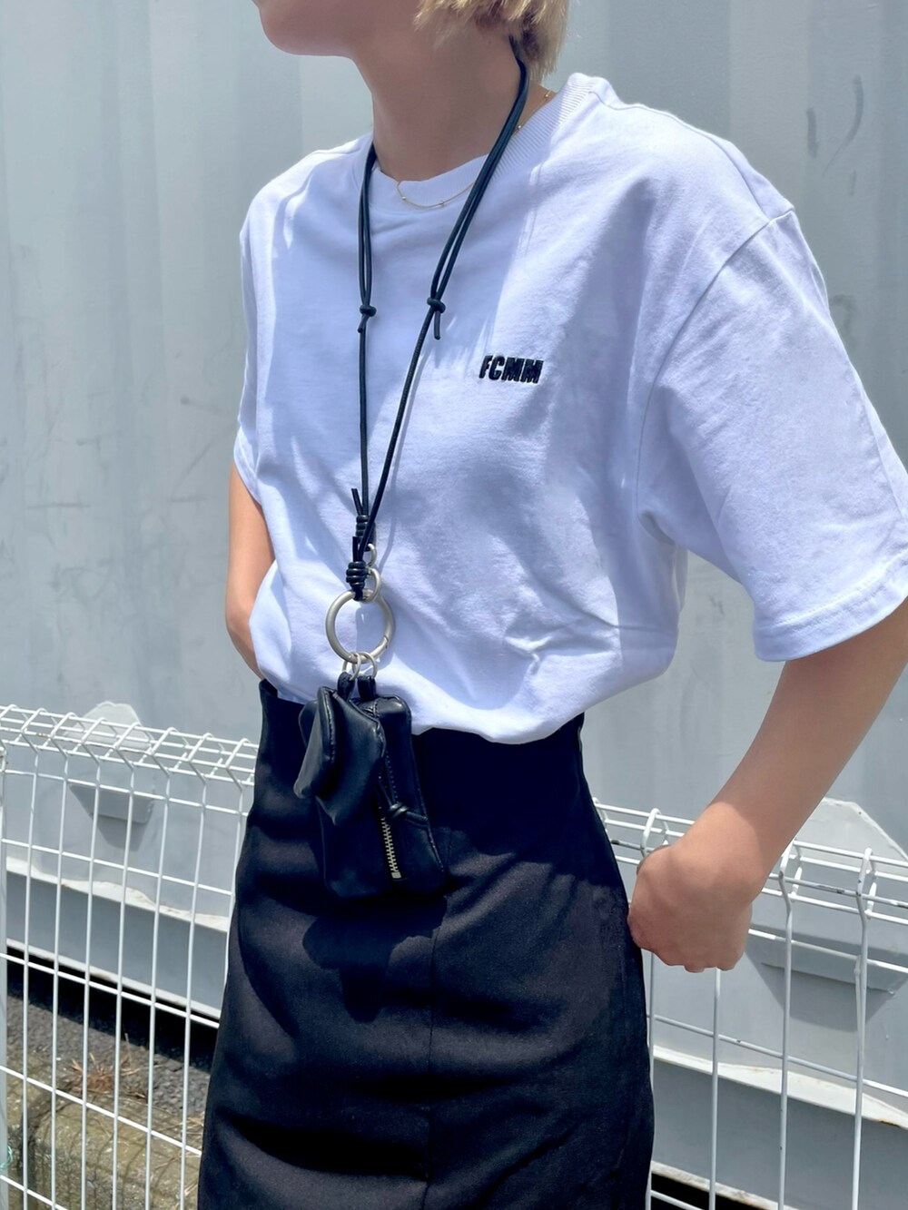 ホワイト系のTシャツ/カットソー、ブラック系のスカート、ブラック系のスニーカーを着用したレディースの春コーディネートの3枚目の写真