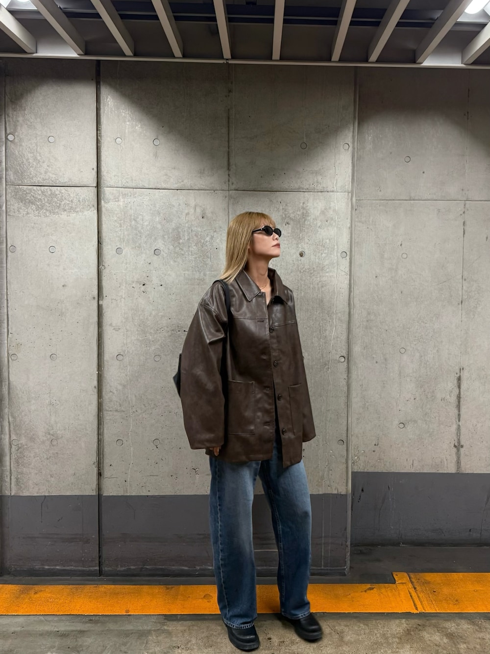 ブラウン系のステンカラーコート、ブラック系のサンダルを着用したレディースの秋コーディネートの2枚目の写真