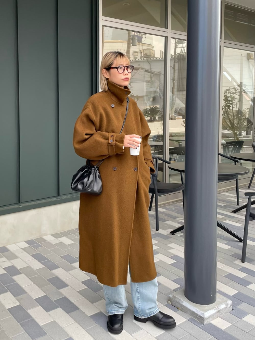 ブラウン系のジャケット/アウター、ブラック系のショルダーバッグ、ブルー系のデニムパンツを着用したレディースの冬コーディネートの2枚目の写真