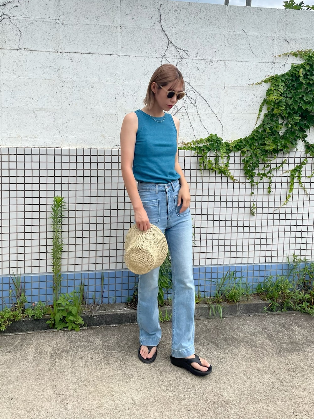 ブルー系のタンクトップ、ブルー系のデニムパンツ、ブラック系のサンダルを着用したレディースの夏コーディネートの3枚目の写真
