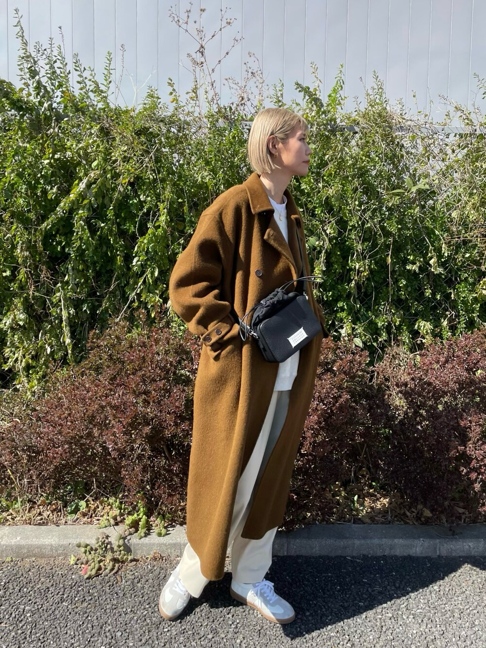 ホワイト系のシューズ、ブラウン系のジャケット/アウター、ブラック系のショルダーバッグを着用したレディースの冬コーディネートの2枚目の写真