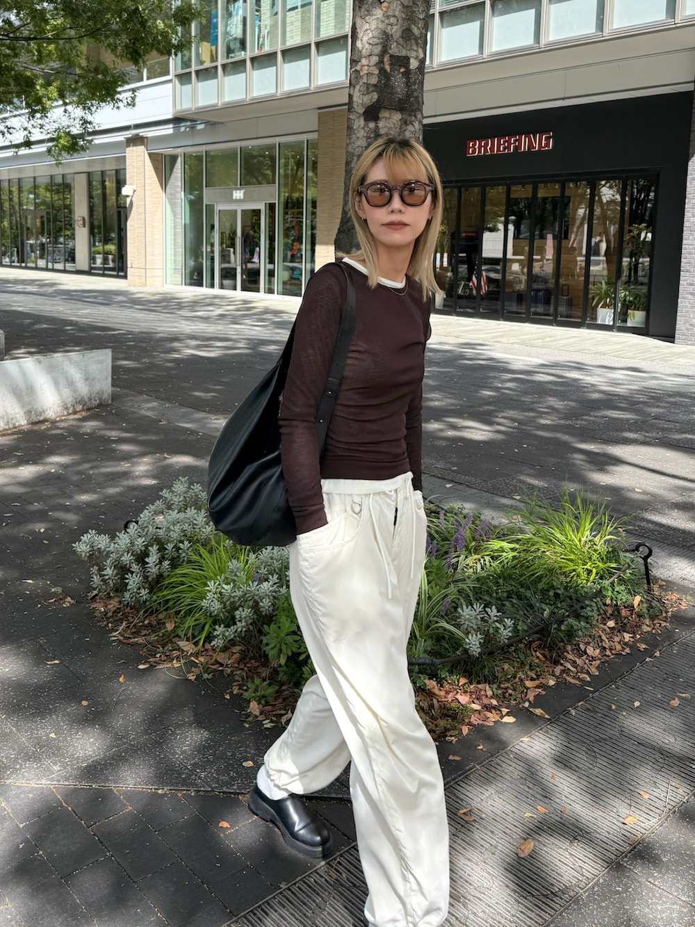 ブラウン系のTシャツ/カットソー、ブラック系のショルダーバッグ、ホワイト系のパンツを着用したレディースの秋コーディネートの2枚目の写真