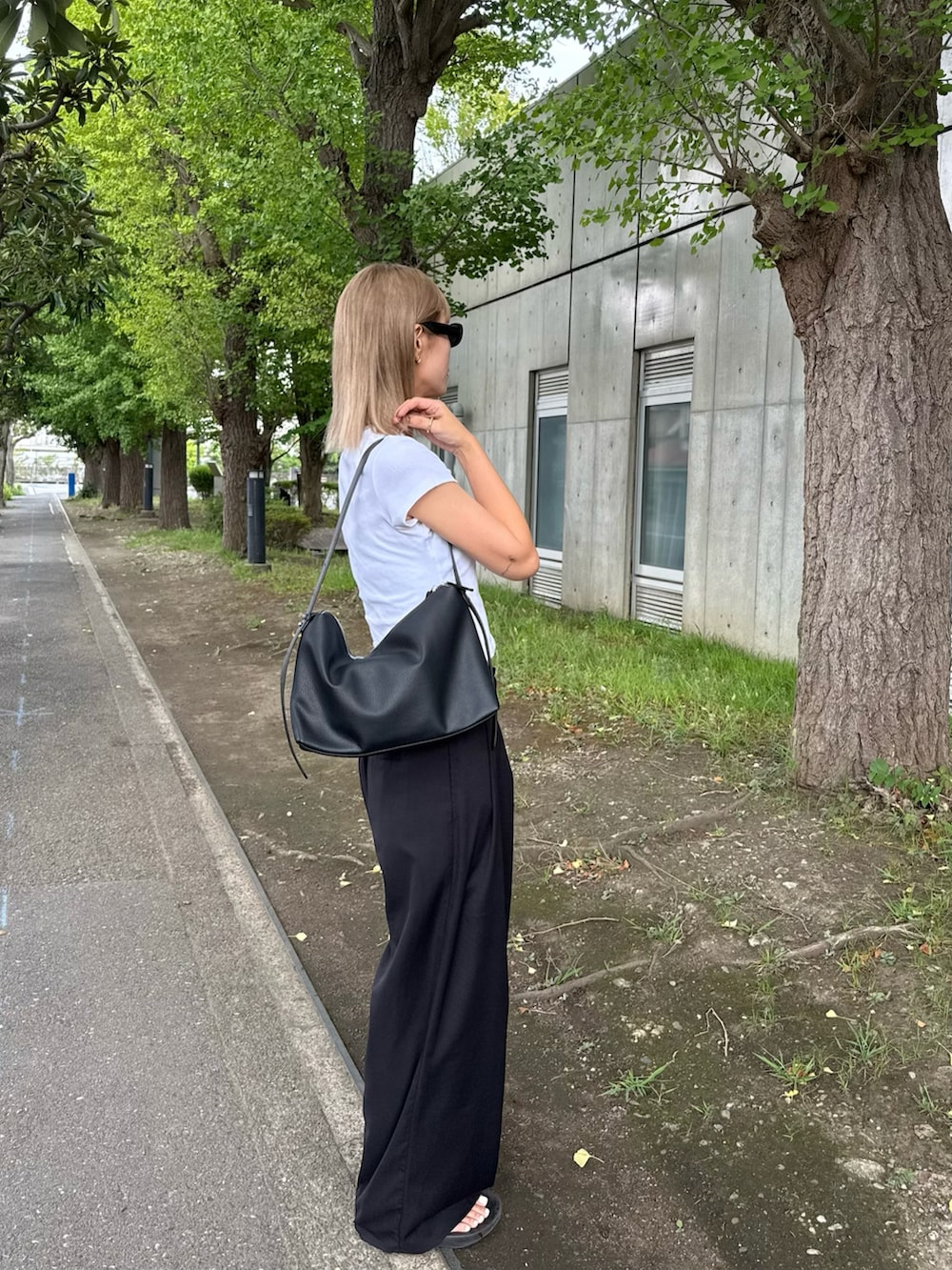 ブラック系のスラックス、ブラック系のショルダーバッグ、ホワイト系のボクサーパンツを着用したレディースの夏コーディネートの2枚目の写真