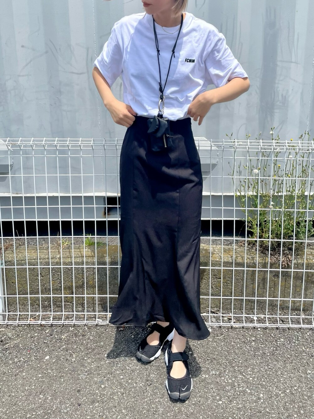 ホワイト系のTシャツ/カットソー、ブラック系のスカート、ブラック系のスニーカーを着用したレディースの春コーディネートの2枚目の写真