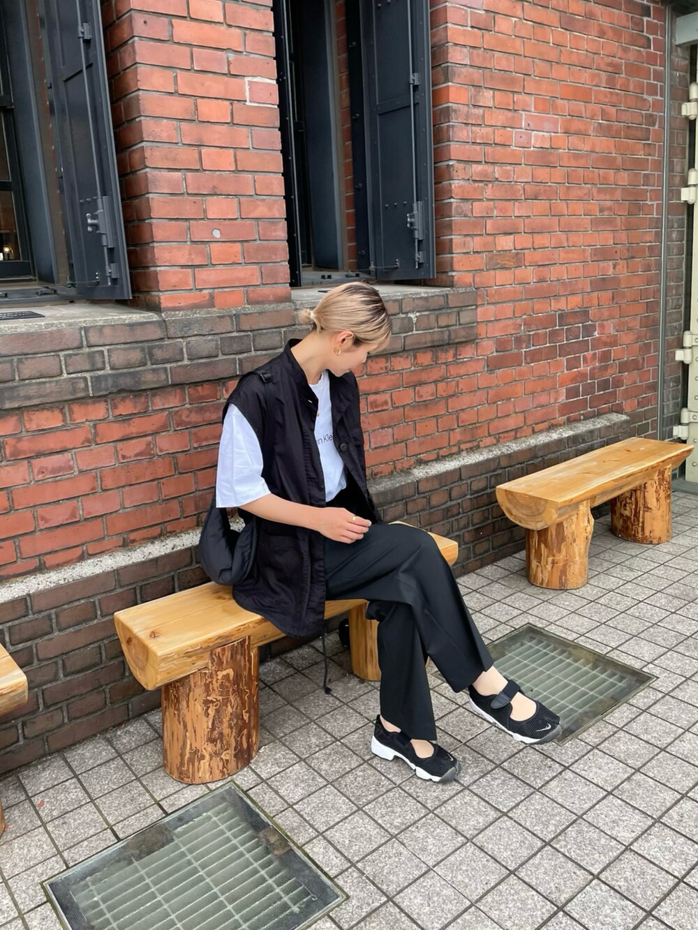 ブラック系のベスト、ブラック系のスニーカー、ホワイト系のTシャツ/カットソーを着用したレディースの夏コーディネートの2枚目の写真