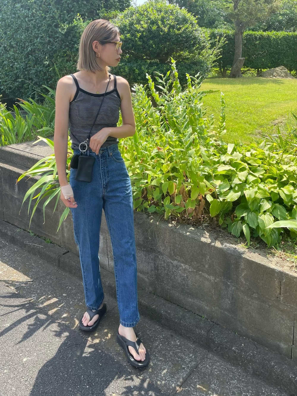 ブラック系のキャミソール、ブルー系のデニムパンツ、ブラック系のサンダルを着用したレディースの夏コーディネートの3枚目の写真