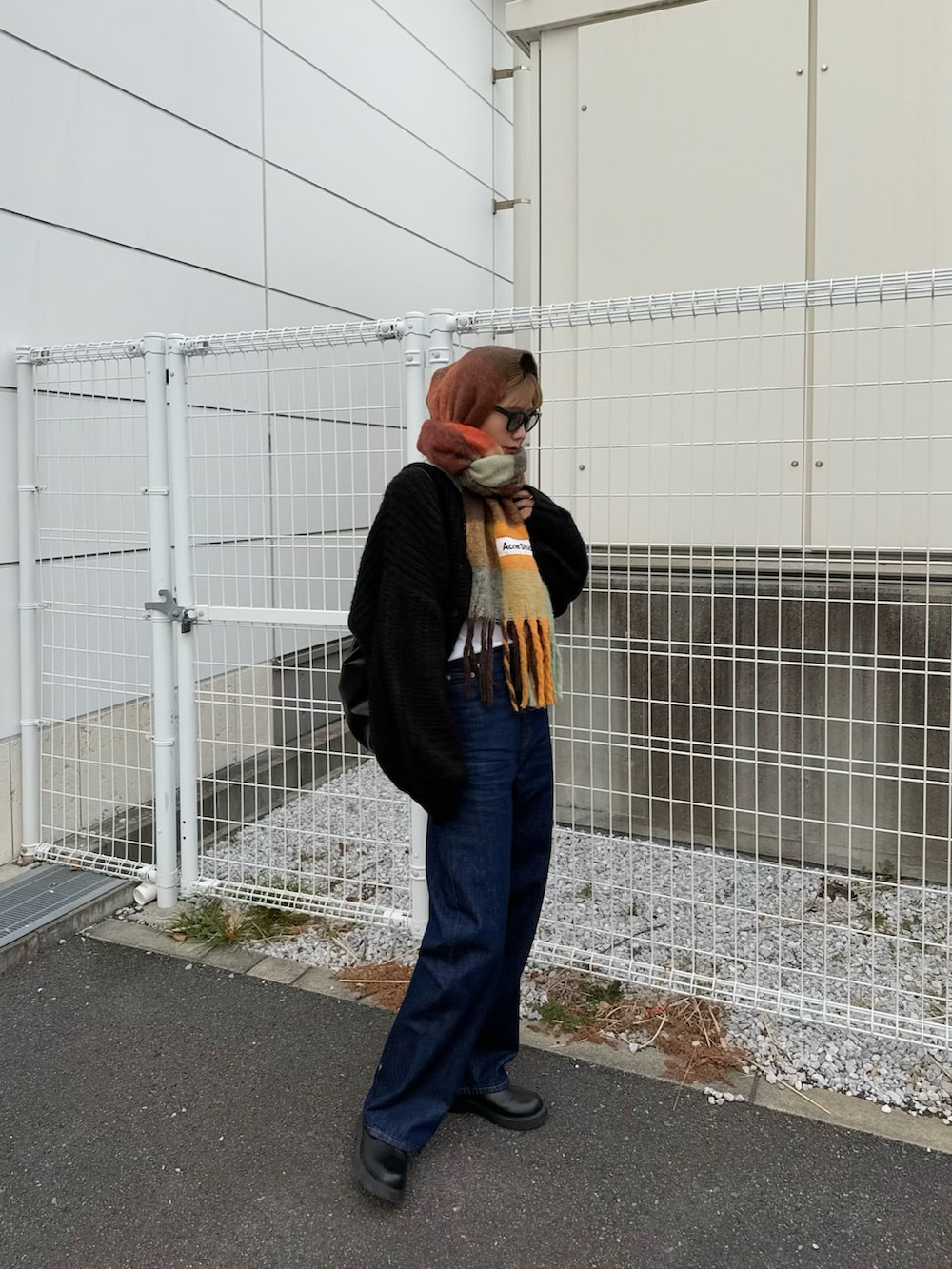 ブルー系のデニムパンツ、ブラック系のサンダル、ブラック系のカーディガン/ボレロを着用したレディースの冬コーディネートの3枚目の写真