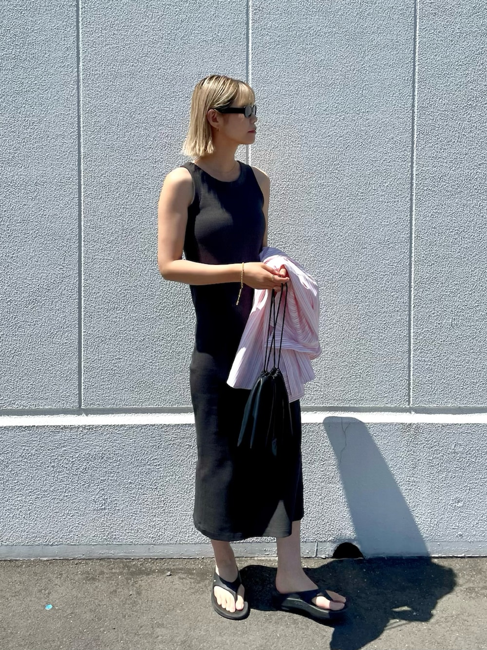 グレー系のワンピース、ブラック系のショルダーバッグ、ピンク系のシャツ/ブラウスを着用したレディースの春コーディネートの2枚目の写真