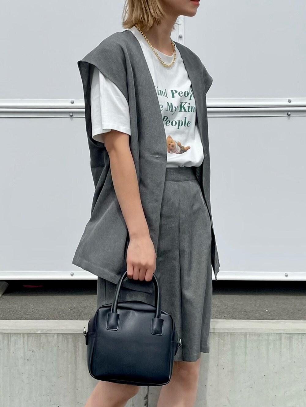 グレー系のセットアップ、ホワイト系のTシャツ/カットソー、ブラック系のスニーカーを着用したレディースの春コーディネートの2枚目の写真