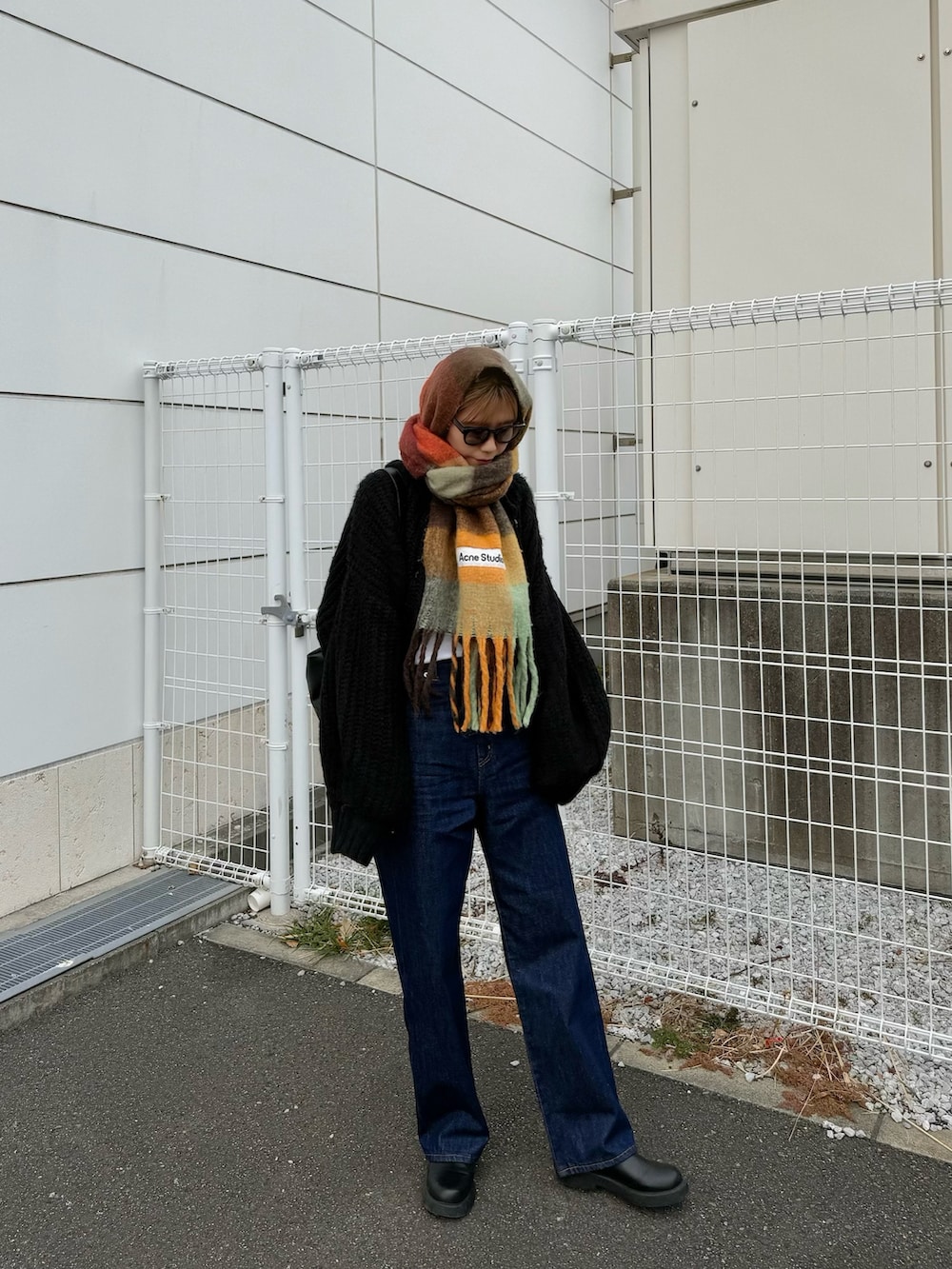 ブルー系のデニムパンツ、ブラック系のサンダル、ブラック系のカーディガン/ボレロを着用したレディースの冬コーディネートの2枚目の写真