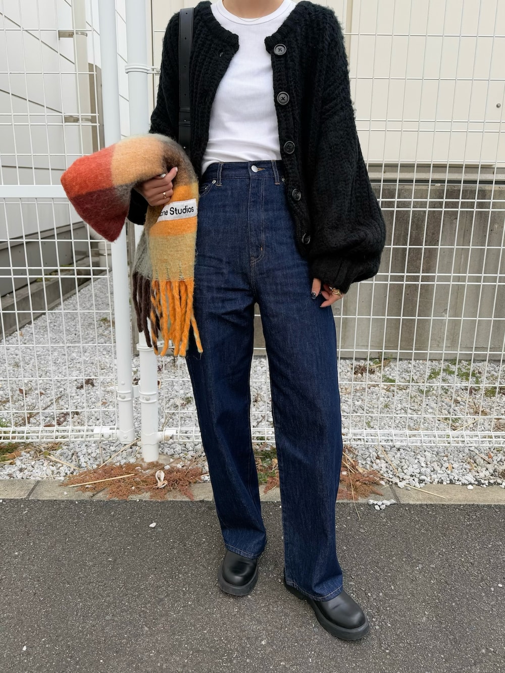 ブルー系のデニムパンツ、ブラック系のサンダル、ブラック系のカーディガン/ボレロを着用したレディースの冬コーディネートの4枚目の写真