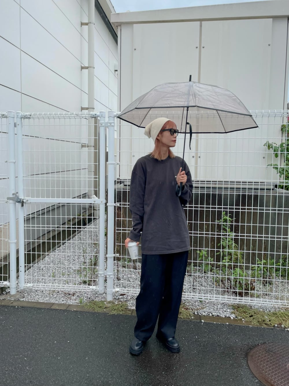 ブラック系のTシャツ/カットソー、ブラック系のサンダル、ブラウン系の長傘を着用したレディースの秋コーディネートの3枚目の写真