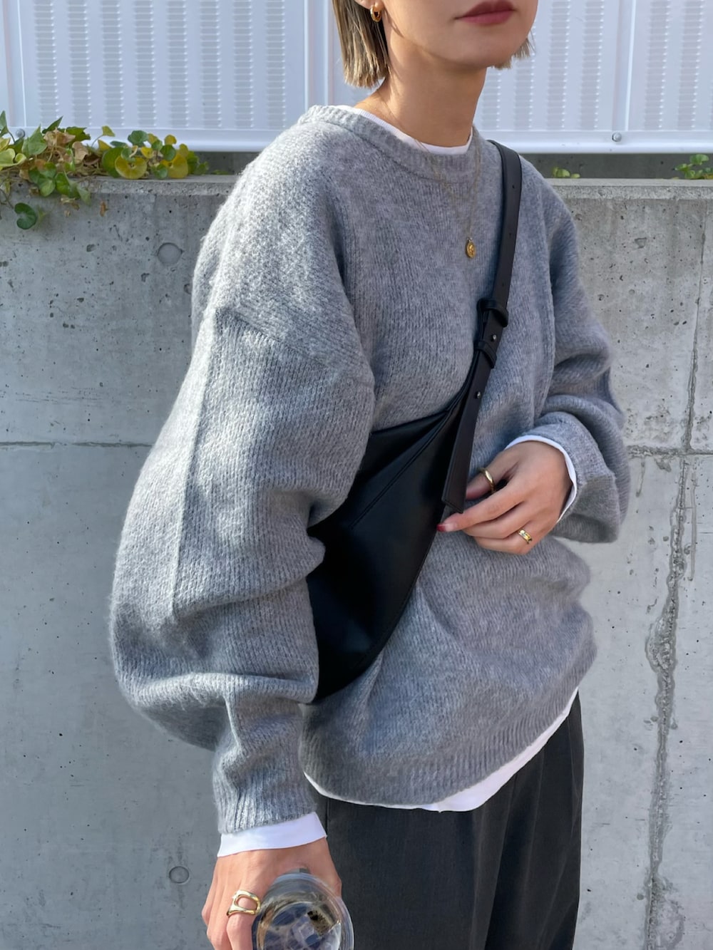 グレー系のパンツ、ブラック系のブーツ、ブラック系のショルダーバッグを着用したレディースの冬コーディネートの3枚目の写真