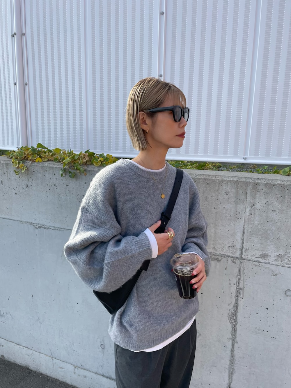 グレー系のパンツ、ブラック系のブーツ、ブラック系のショルダーバッグを着用したレディースの冬コーディネートの2枚目の写真