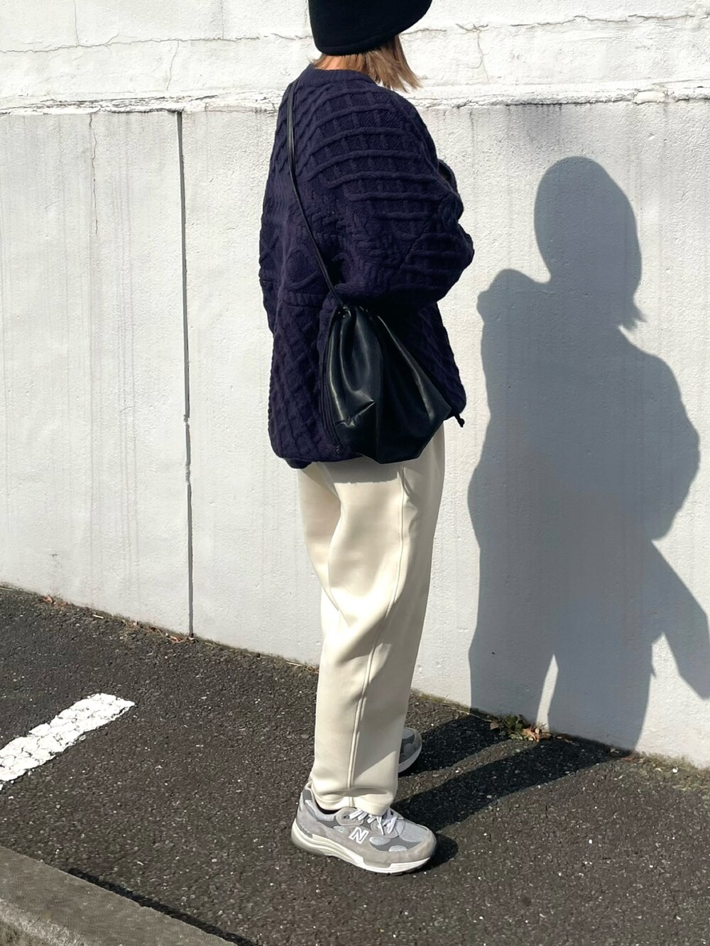 ブルー系のニット/セーター、ブラック系のショルダーバッグ、ホワイト系のパンツを着用したレディースの秋コーディネートの3枚目の写真