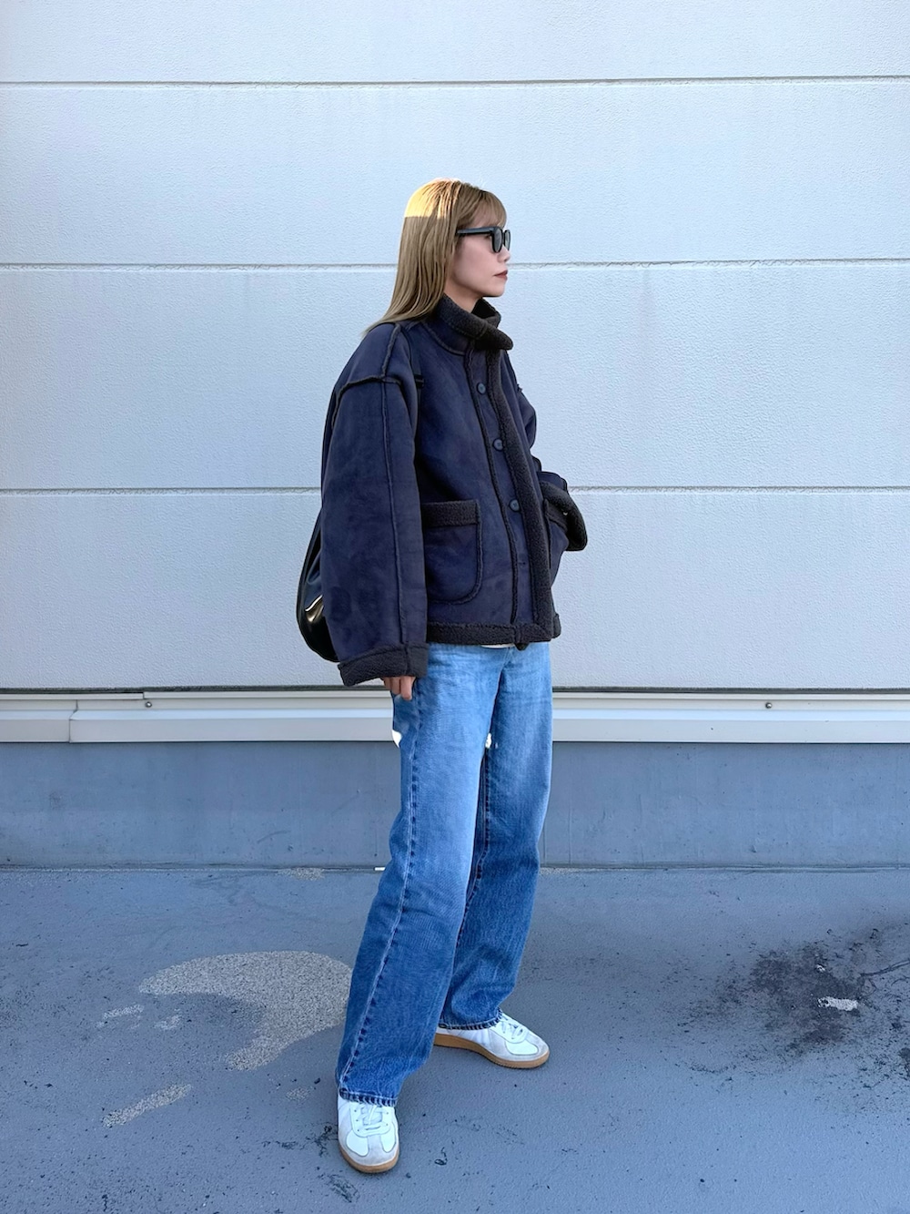 グレー系のムートンコート、ホワイト系のスニーカーを着用したレディースの冬コーディネートの2枚目の写真