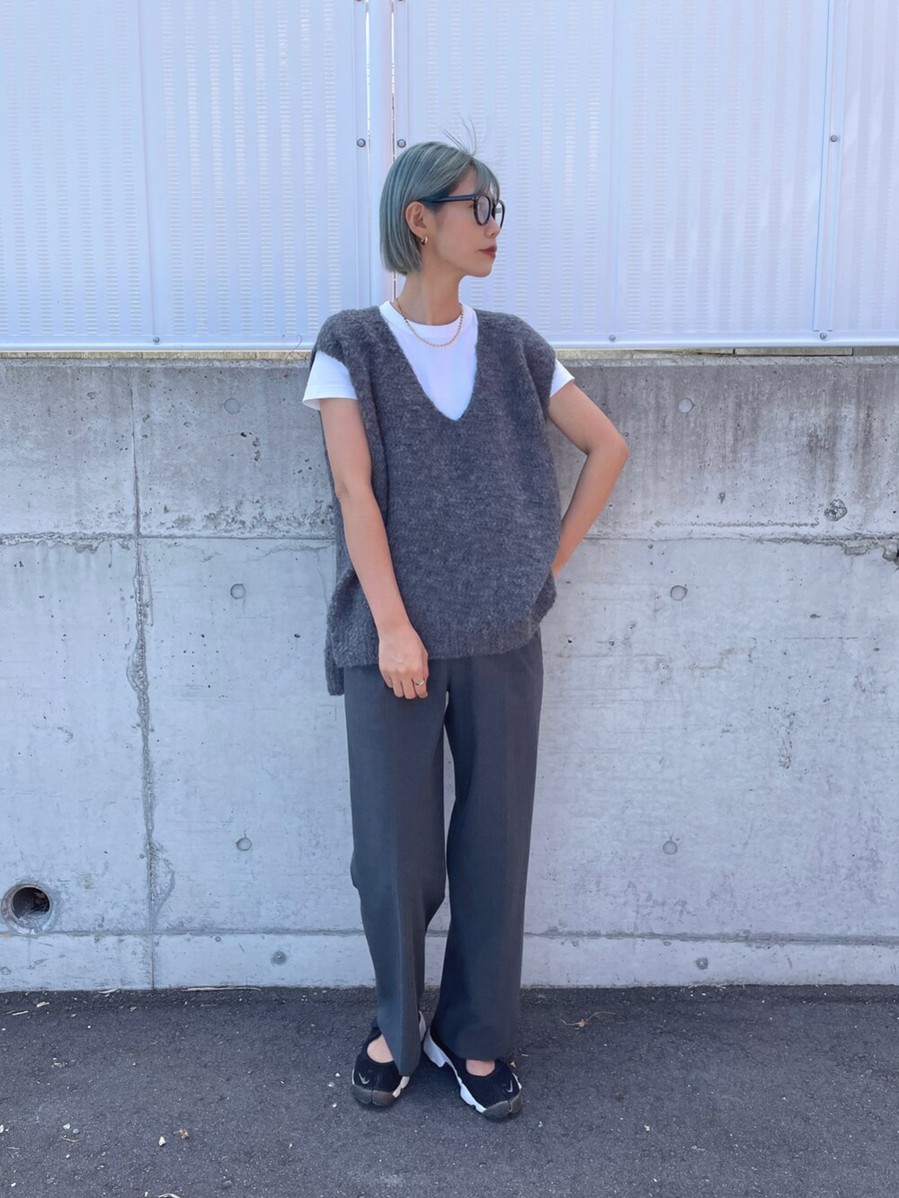 ブラック系のスニーカー、グレー系のベスト、グレー系のパンツを着用したレディースの秋コーディネートの2枚目の写真