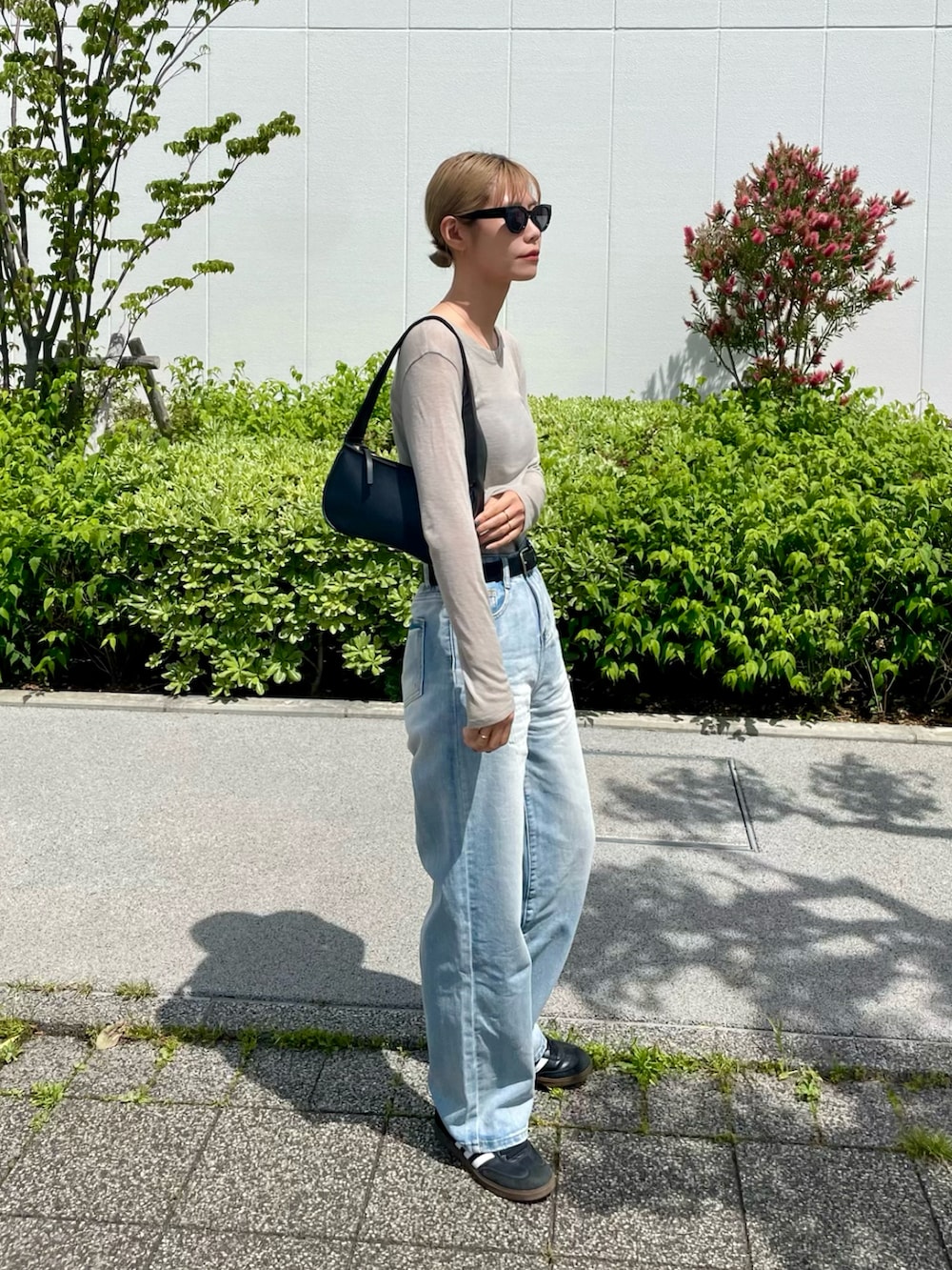 ブルー系のデニムパンツ、ブラック系のスニーカー、ベージュ系のトップスを着用したレディースの春コーディネートの2枚目の写真