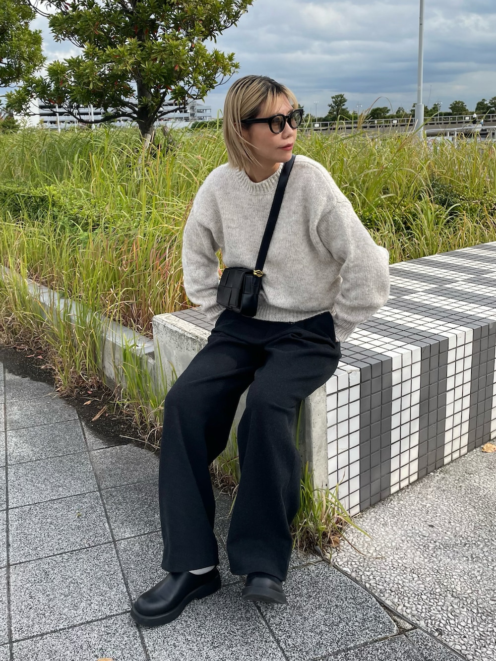 ホワイト系のニット/セーター、グレー系のパンツ、ブラック系のサンダルを着用したレディースの秋コーディネートの2枚目の写真