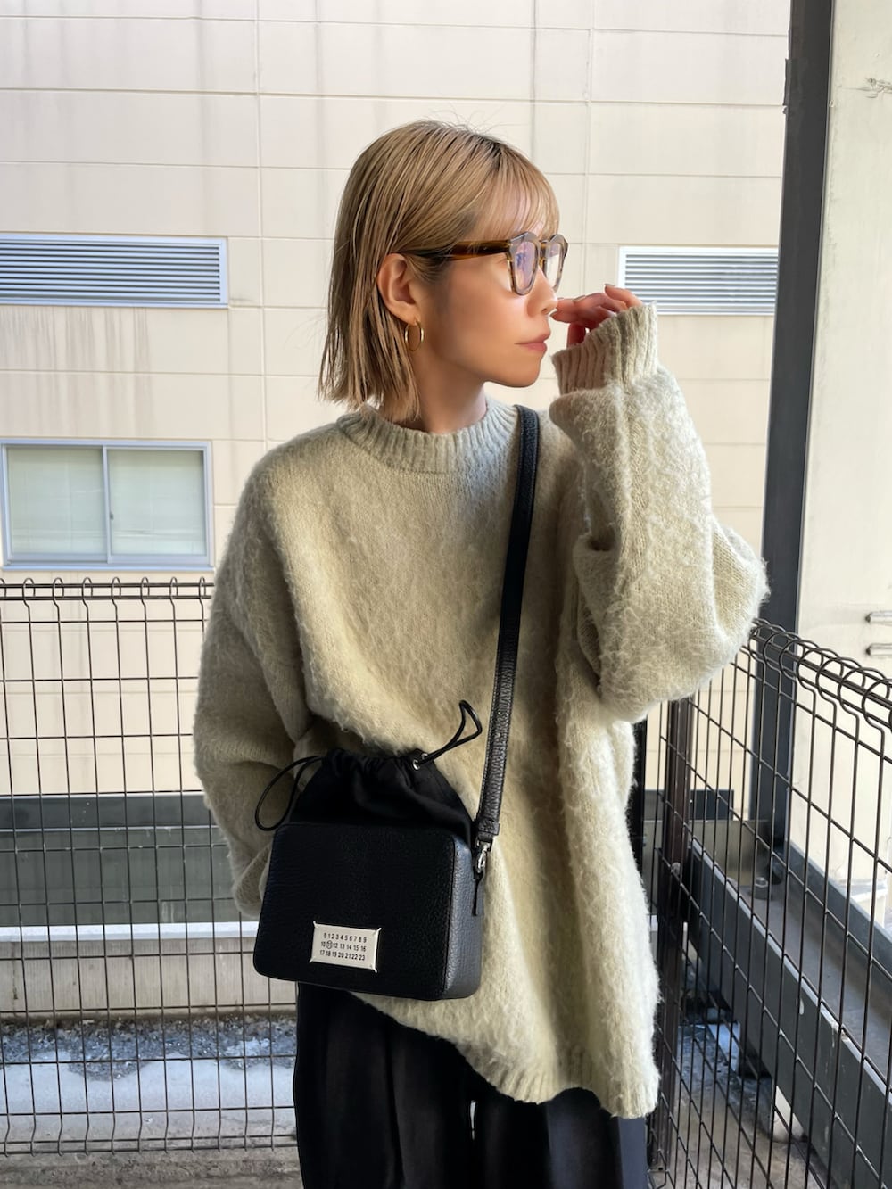 ブラック系のショルダーバッグ、ベージュ系のニット/セーター、ブラック系のその他パンツを着用したレディースの冬コーディネートの2枚目の写真