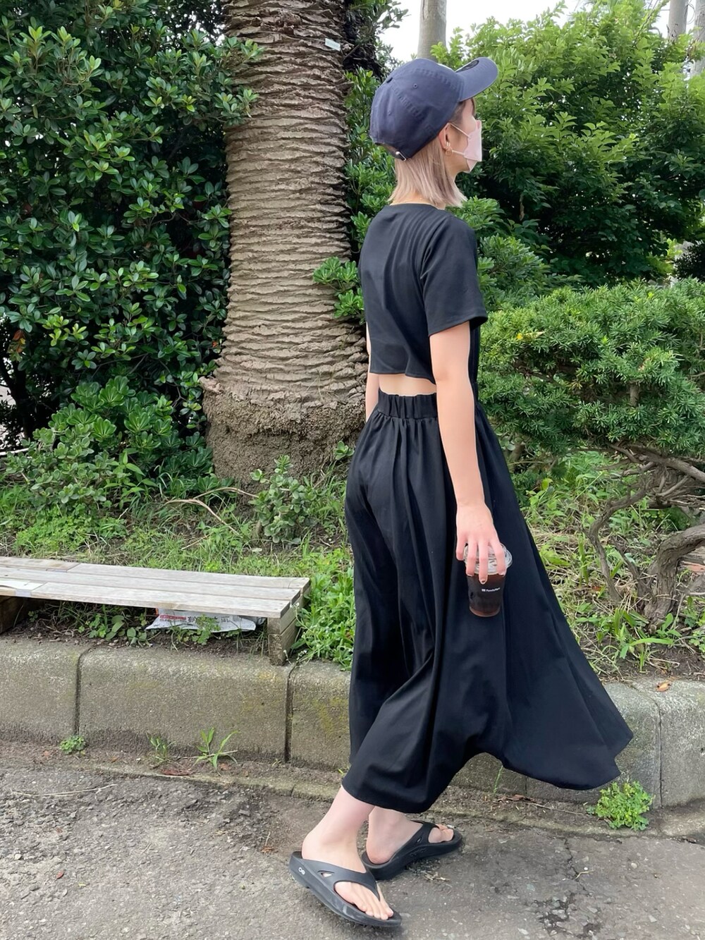 ブラック系のワンピース、ブラック系のサンダル、ブルー系のキャップを着用したレディースの夏コーディネートの4枚目の写真