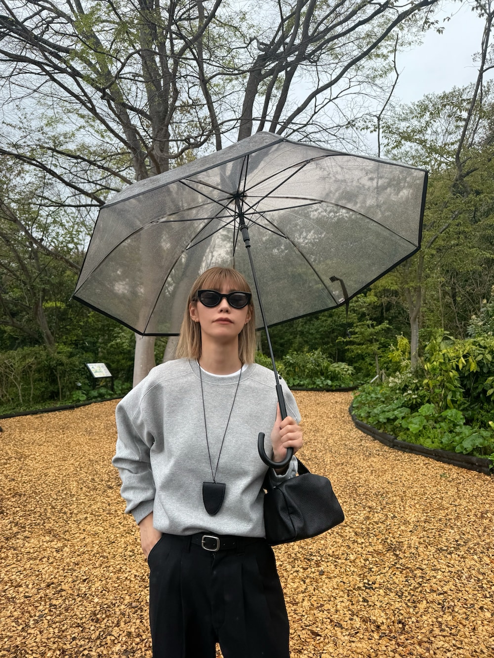 ブラック系のその他パンツ、グレー系のトップス、ブラウン系の長傘を着用したレディースの春コーディネートの2枚目の写真