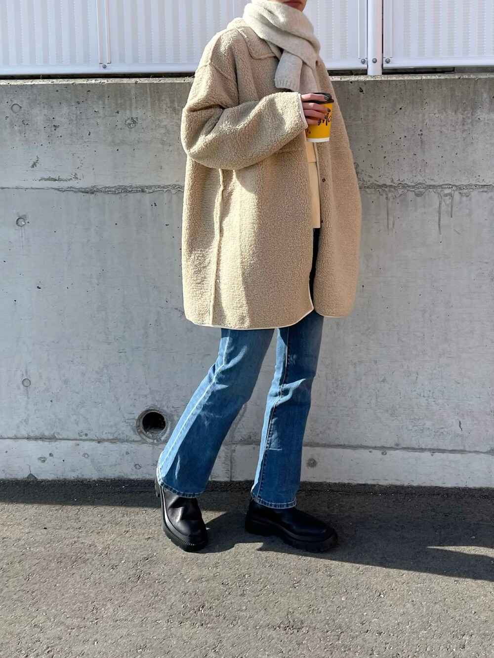 ベージュ系のムートンコート、ブルー系のパンツ、ブラック系のブーツを着用したレディースの冬コーディネートの2枚目の写真