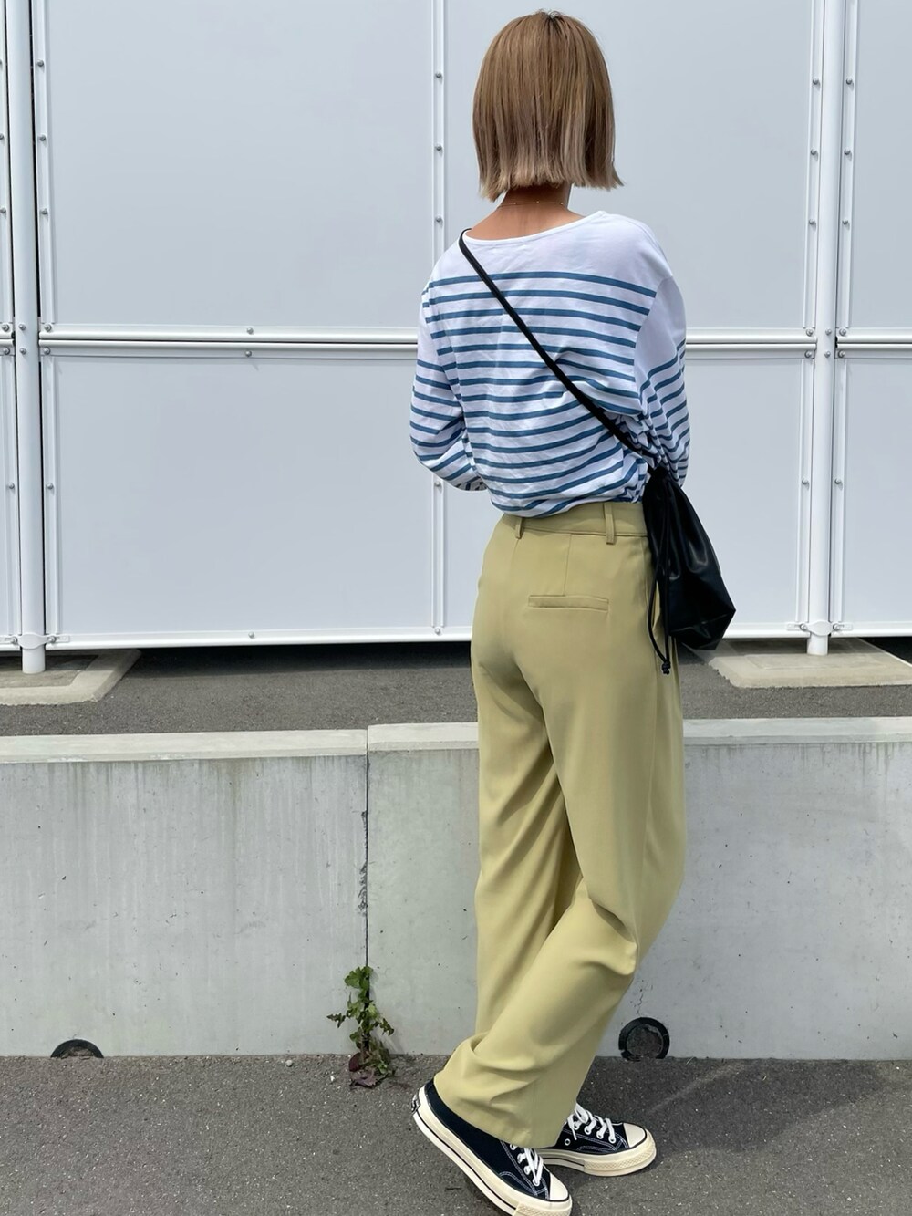 ブルー系のトップス、ブラック系のショルダーバッグ、ブラック系のシューズを着用したレディースの春コーディネートの3枚目の写真