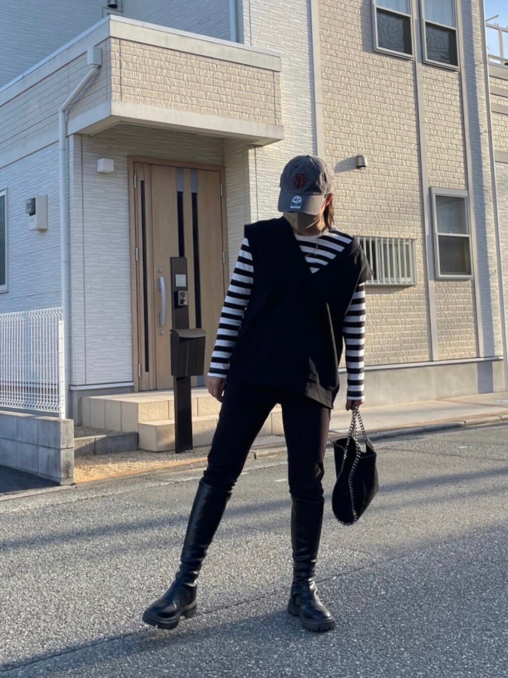 ブラック系のショルダーバッグ、ブラック系のブーツ、ブラック系のパンツを着用したレディースの冬コーディネートの2枚目の写真