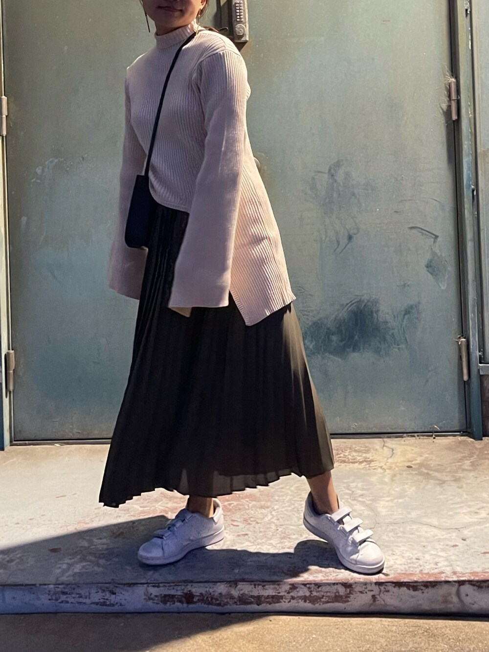 グリーン系のスカート、ホワイト系のスニーカー、ホワイト系のニット/セーターを着用したレディースの秋コーディネートの2枚目の写真