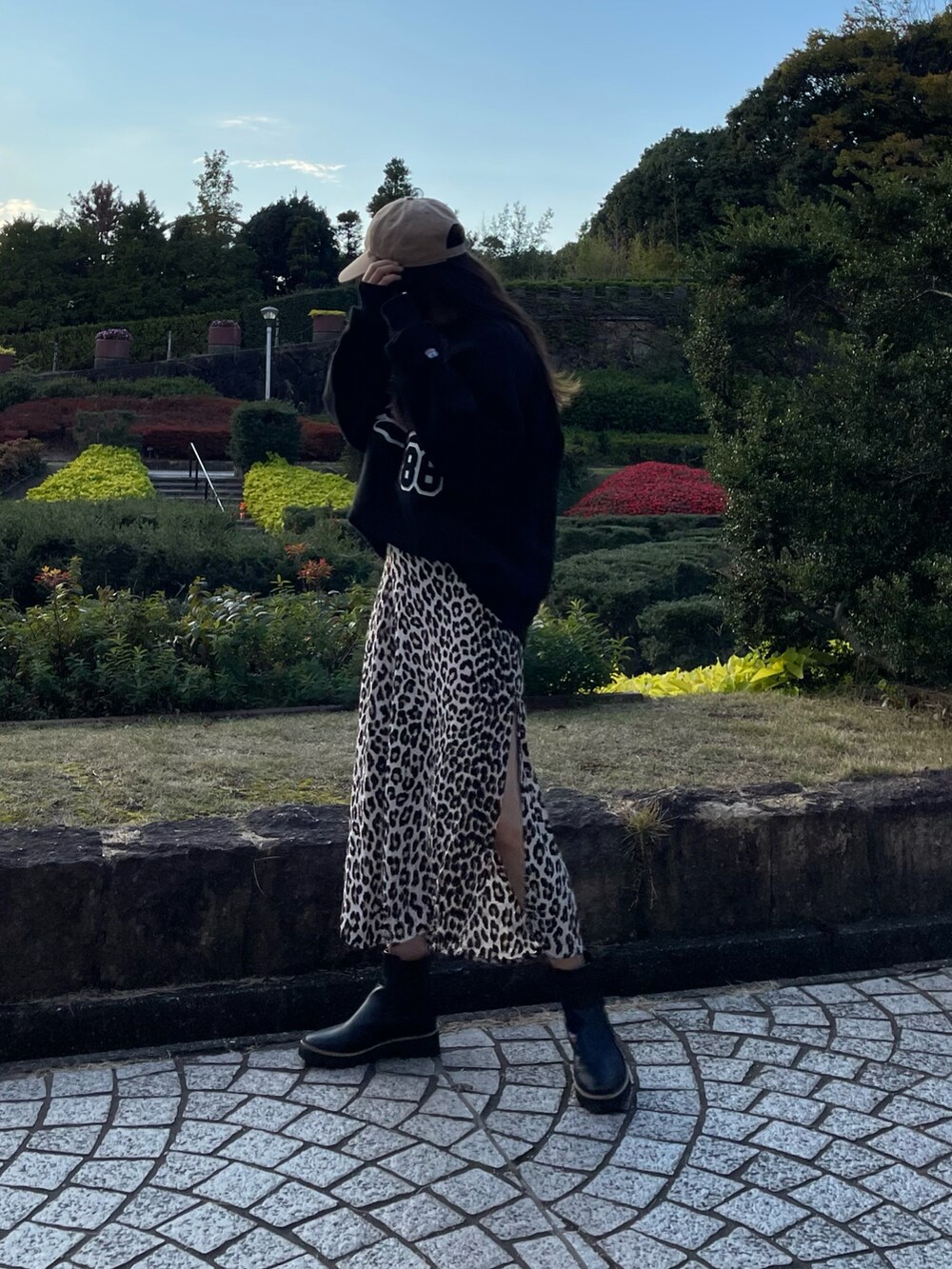 ベージュ系のスカート、ブラック系のスウェット、ブラック系のブーツを着用したレディースの秋コーディネートの3枚目の写真