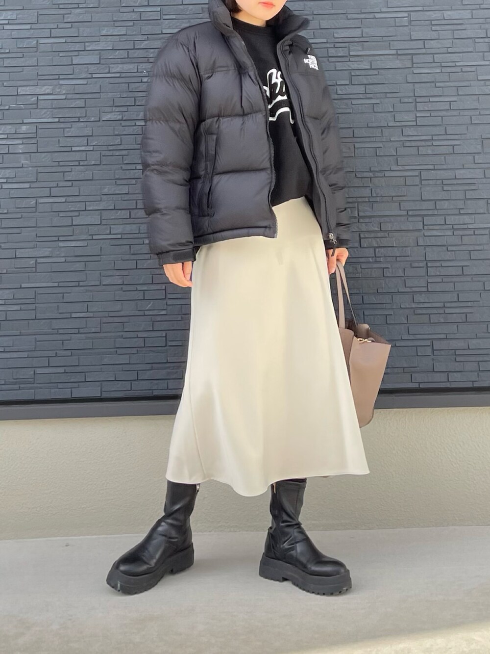 グレー系のトートバッグ、ブラック系のブーツ、ホワイト系のスカートを着用したレディースの冬コーディネートの2枚目の写真