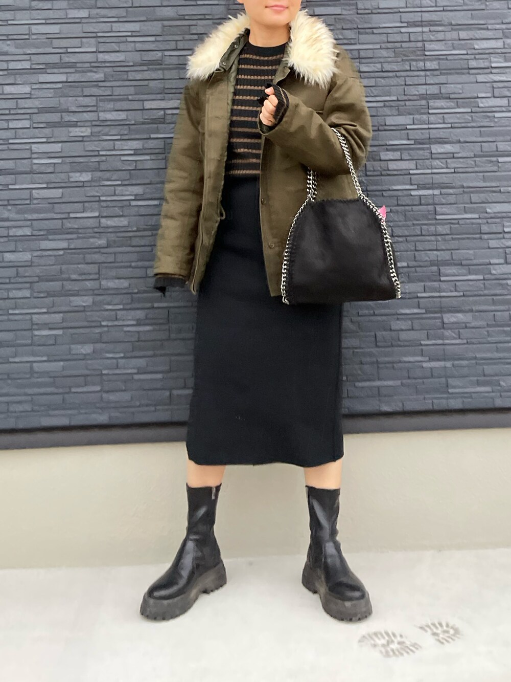 グリーン系のジャケット/アウター、ブラック系のハンドバッグ、ブラック系のブーツを着用したレディースの冬コーディネートの2枚目の写真
