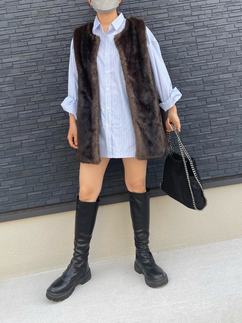 ブラック系のブーツ、ブルー系のシャツ/ブラウス、ブラウン系のベストを着用したレディースの春コーディネートの2枚目の写真