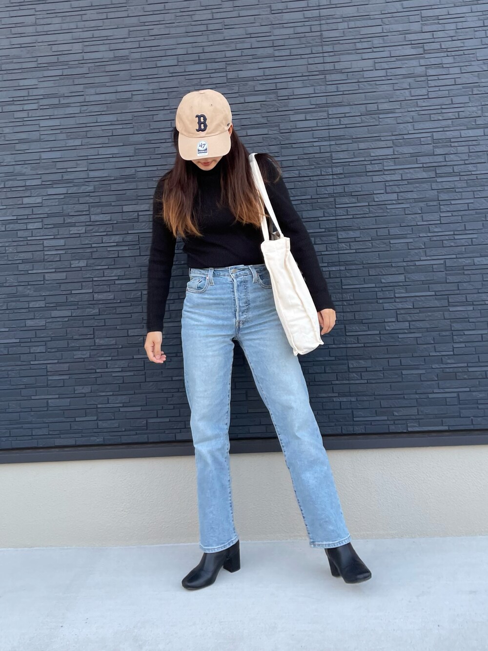 ホワイト系のトートバッグ、ブルー系のデニムパンツ、ブラック系のシューズを着用したレディースの秋コーディネートの2枚目の写真