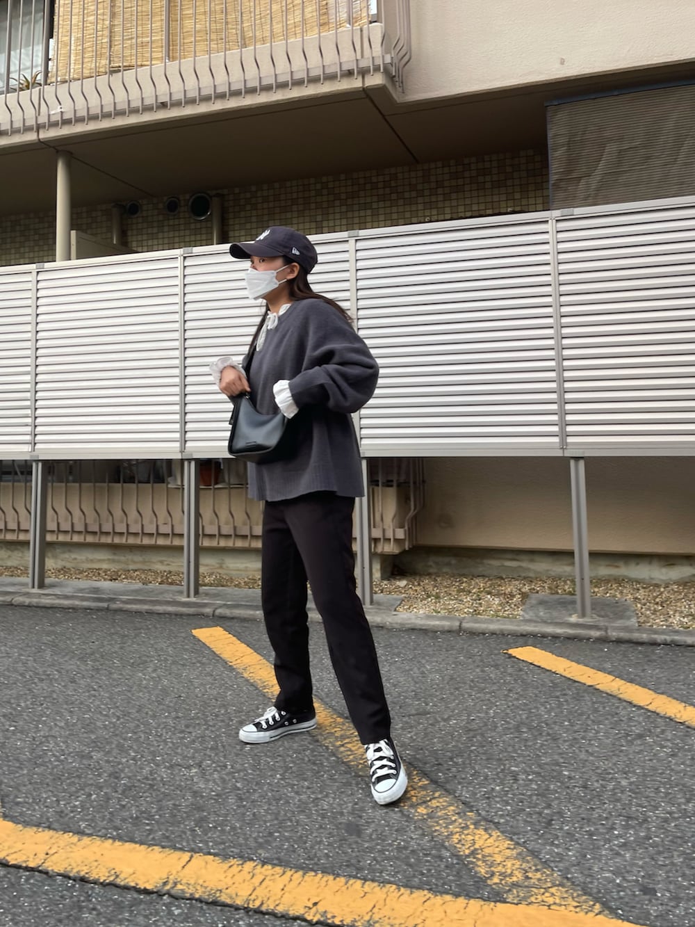 ブラック系のパンツ、ブラック系のスニーカー、グレー系のニット/セーターを着用したレディースの春コーディネートの2枚目の写真