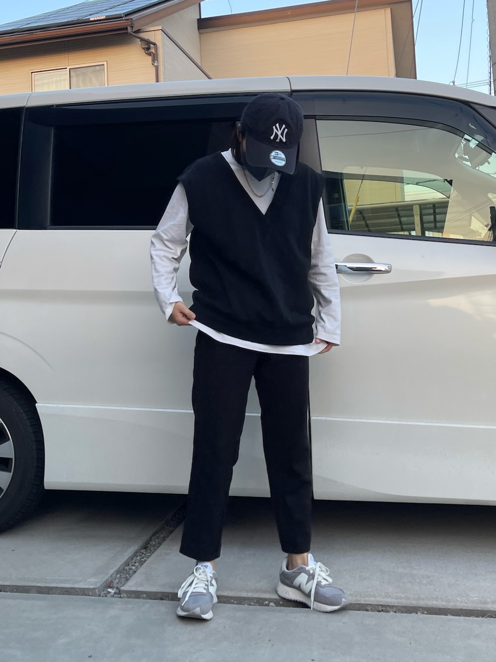 ブラック系のパンツ、グレー系のスニーカー、ブラック系のベストを着用したレディースの春コーディネートの2枚目の写真