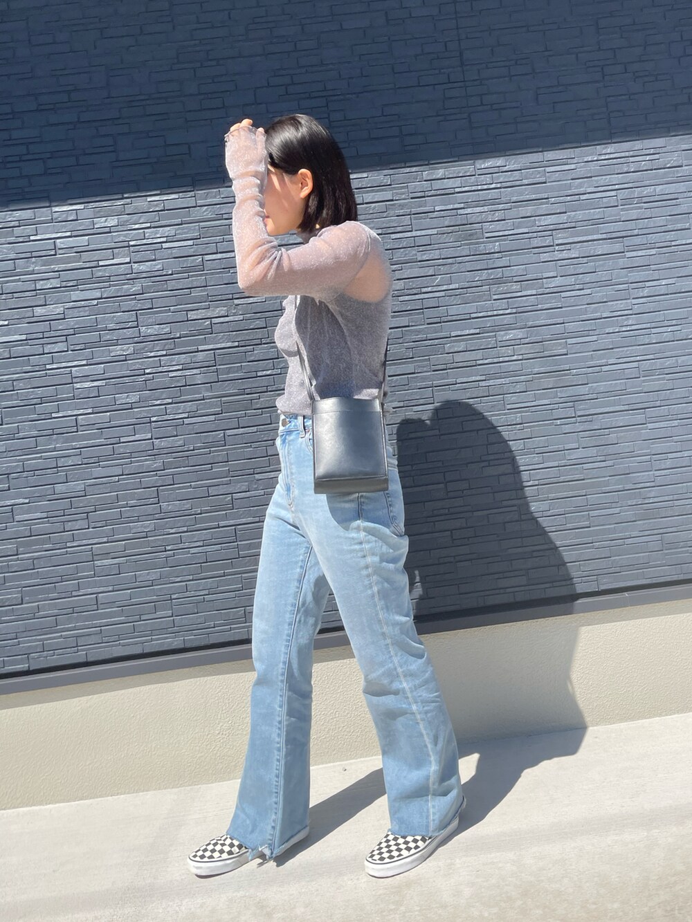 ブルー系のデニムパンツ、ホワイト系のスニーカー、グレー系のトップスを着用したレディースの秋コーディネートの2枚目の写真