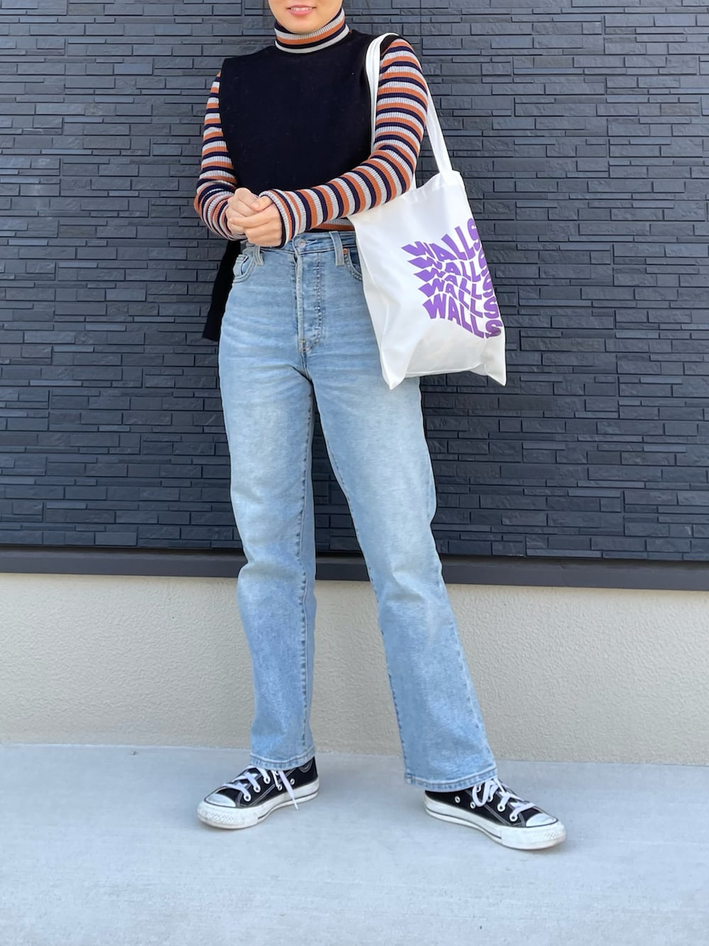 ブルー系のデニムパンツ、ブラック系のスニーカー、オレンジ系のニット/セーターを着用したレディースの冬コーディネートの2枚目の写真