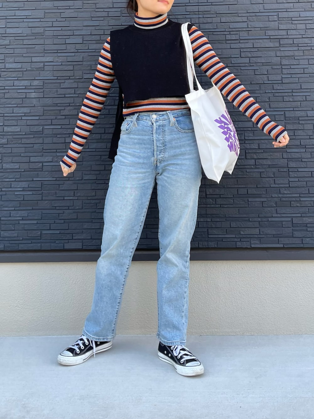 ブルー系のデニムパンツ、ブラック系のスニーカー、オレンジ系のニット/セーターを着用したレディースの冬コーディネートの3枚目の写真