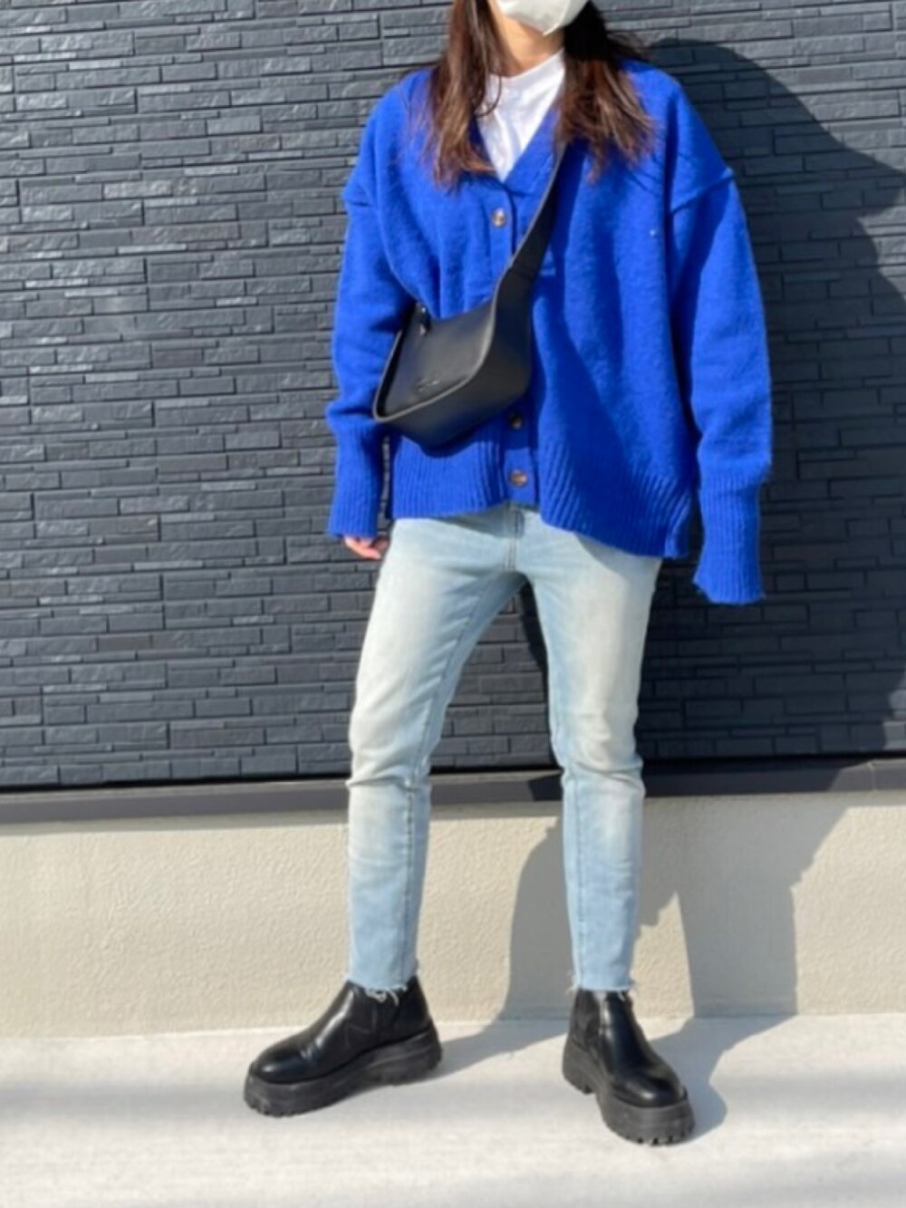 ブルー系のデニムパンツ、ブラック系のブーツ、ブルー系のカーディガン/ボレロを着用したレディースの冬コーディネートの3枚目の写真